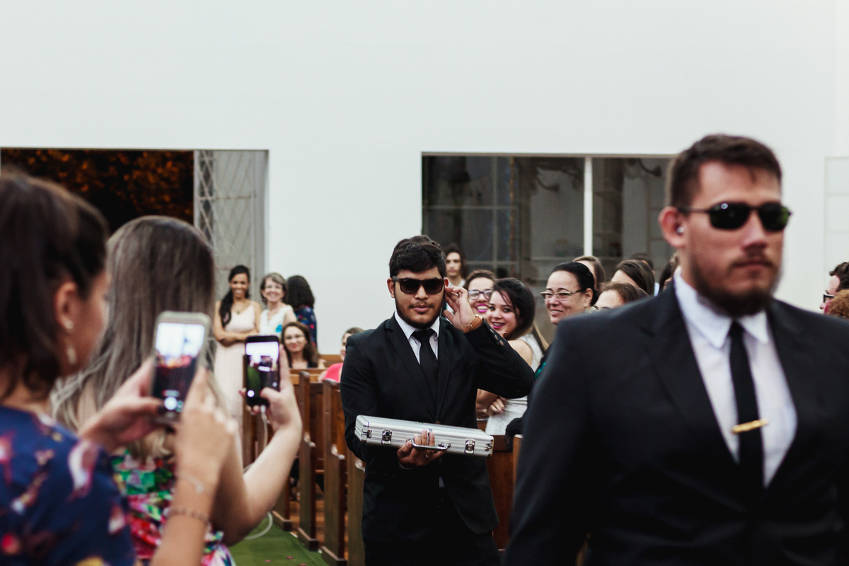 Padrinhos entrando na igreja com alianças com fantasia de agentes secretos