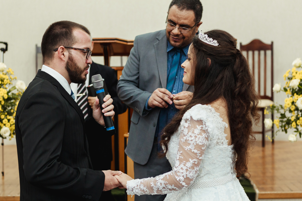 Noivo se declarando para noiva durante cerimônia de casamento ao lado de seu pastor