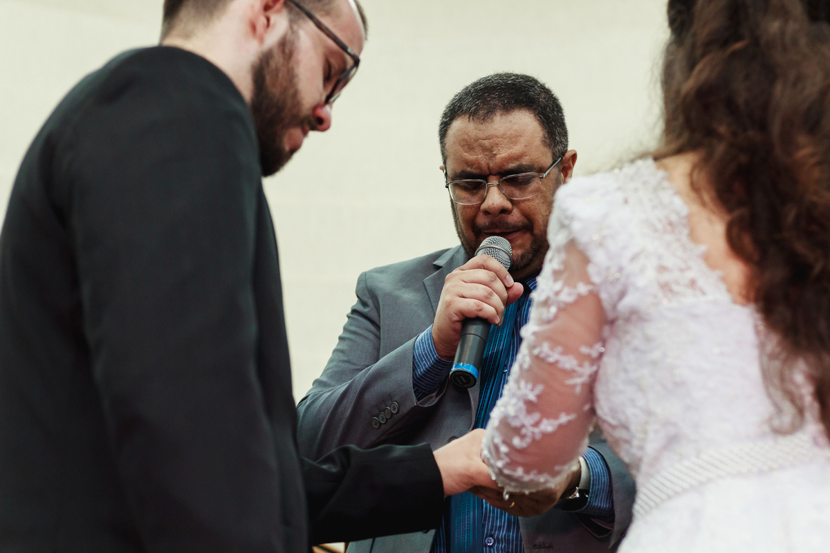 Pastor orando pelos noivos em cerimônia de casamento