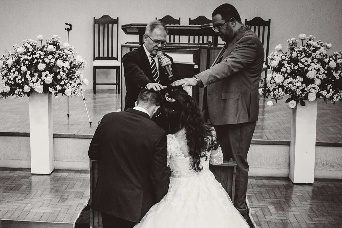Pastores orando pelos noivos durante cerimônia de casamento