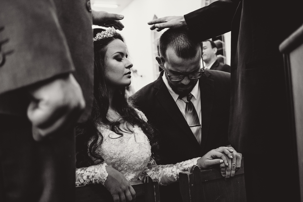 Pastores impondo as mãos sobre os noivos em sinal de oração durante casamento