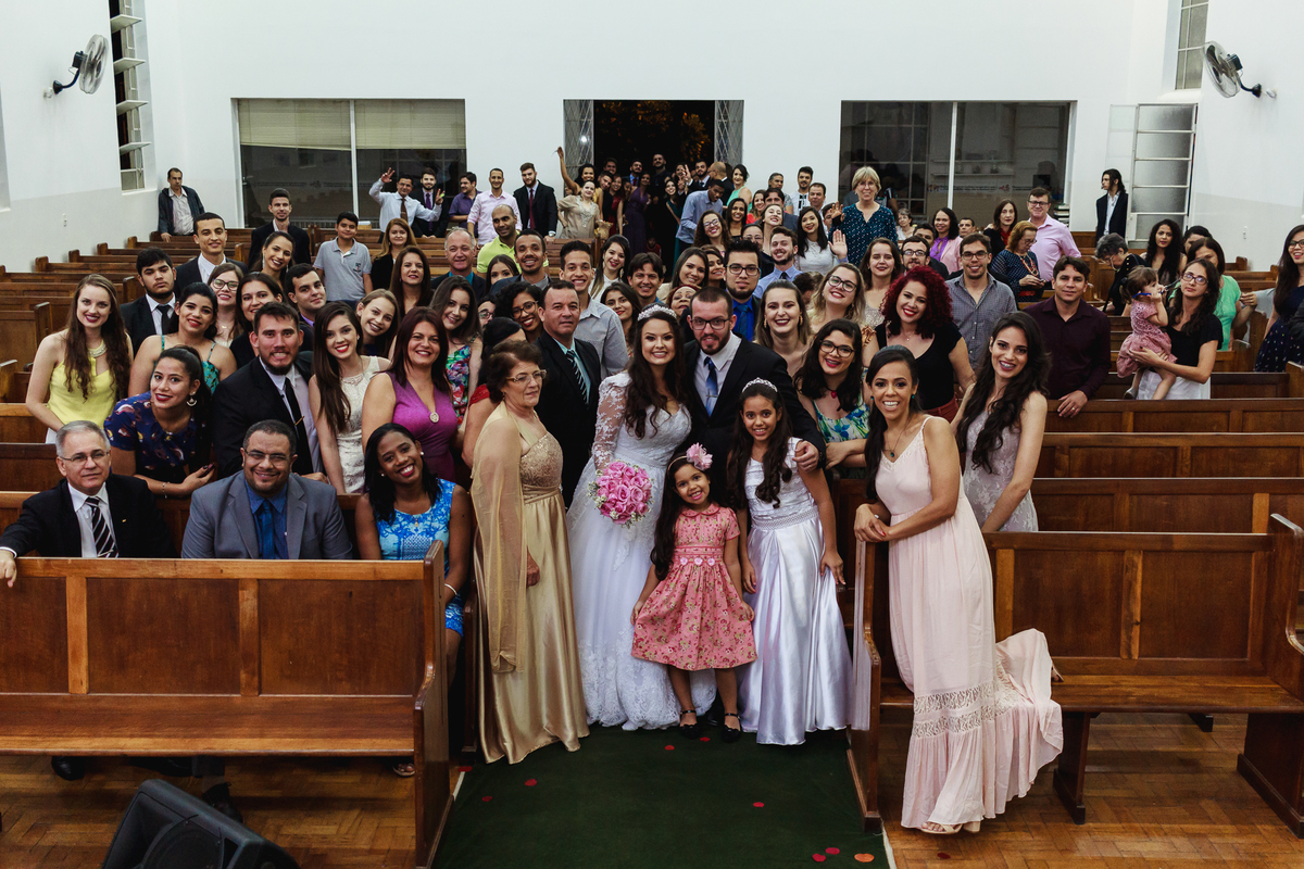 Noiva com todos os padrinhos e pessoas do casamento em uma fotografia na igreja com todos sorrindo para câmera gerando uma foto divertida dos padrinhos
