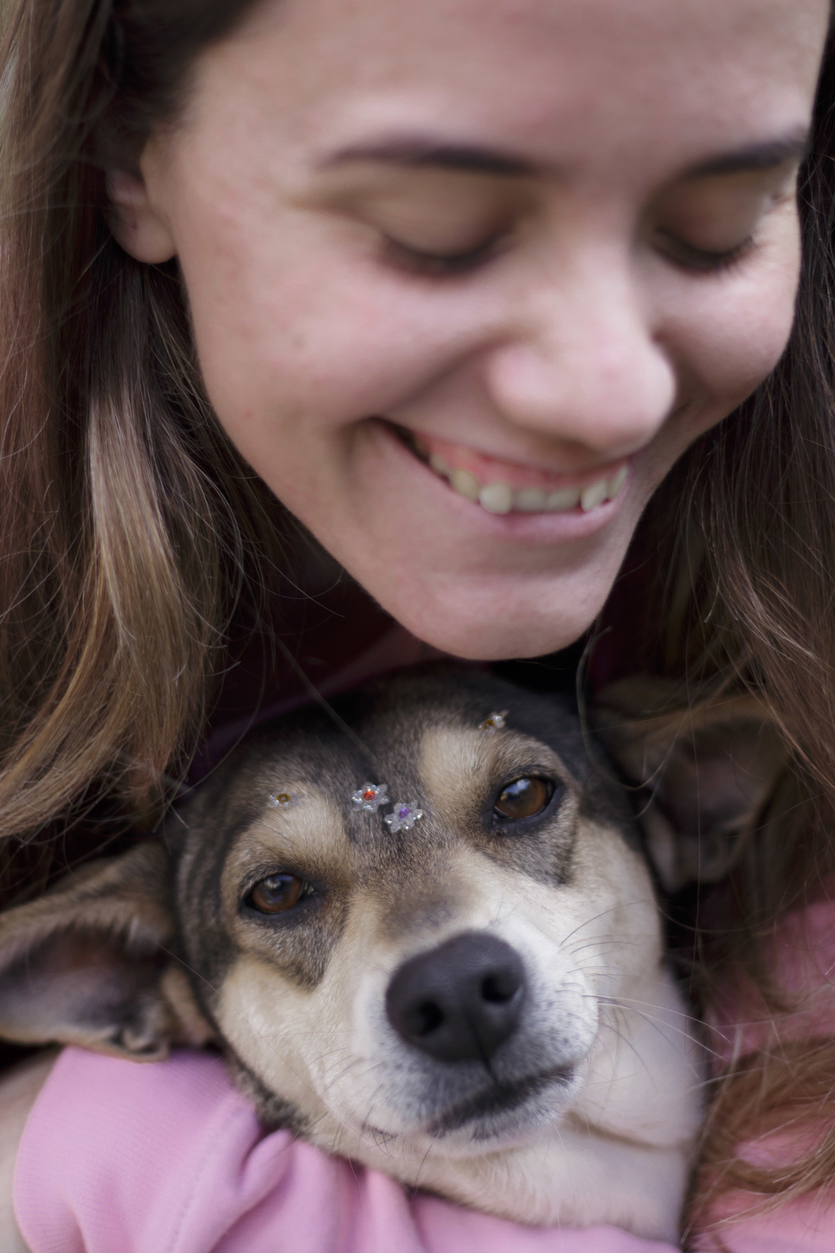  a imagem mostra uma mulher sorrindo enquanto abraça uma cachorrinha que está usando florzinha na testa. ⁣⁣