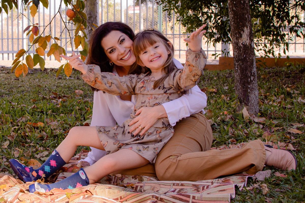mae e filha felizes em baixo de um pé de caqui 