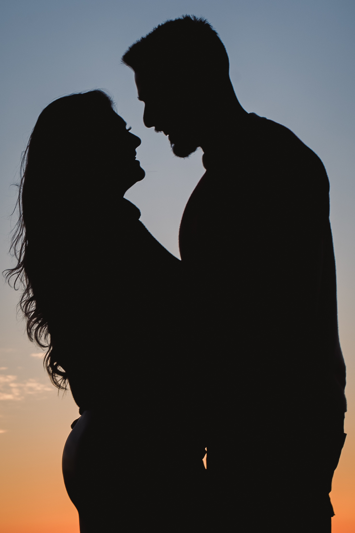 casal no pico de monte claro com o por do sol e o contorno do sol chamado silhueta 