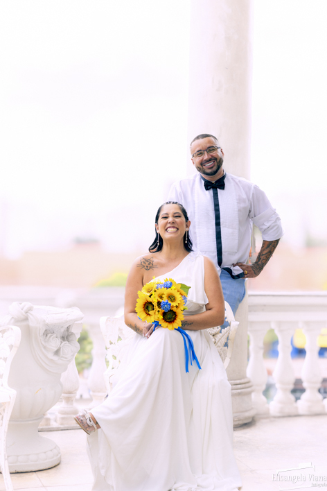 noiva sentada e noivo de pé 