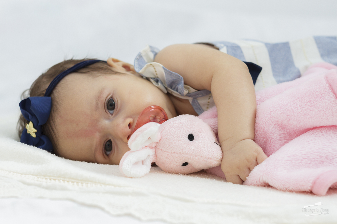 bebê de chupeta e segurando coelhinho rosa