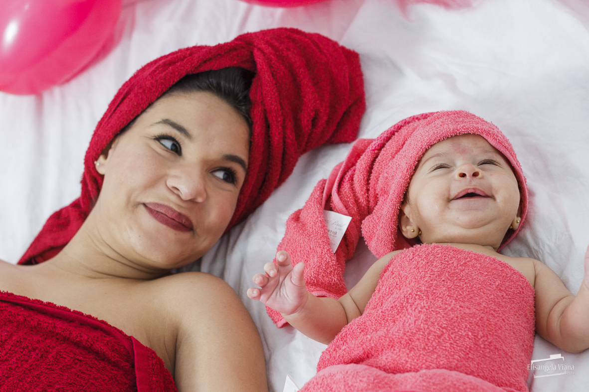 bebê sorrindo enquanto estão de toalhas no cabelo e no corpo