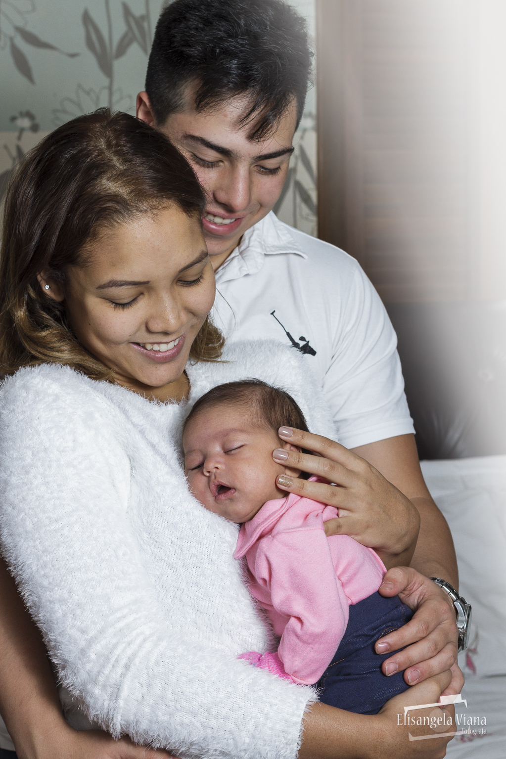 pais sorrindo olhando para bebê no colo da mãe