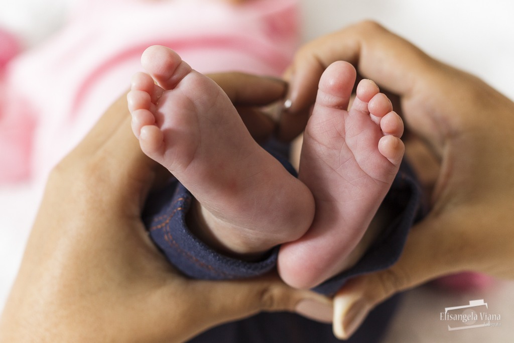 mãe faz coração com a mão em vonta dos pés da bebê