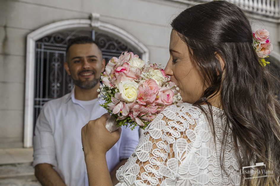 noiva cheira buquê enquanto noivo a observa