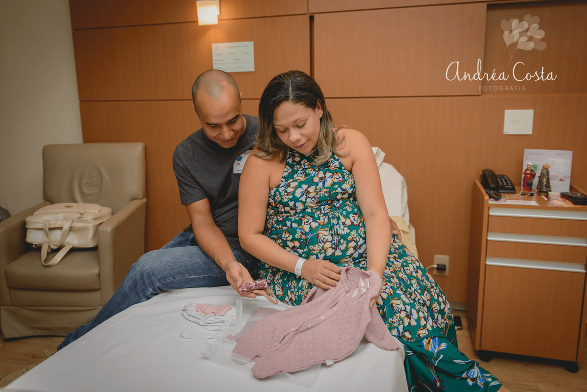 Papai e Mamãe arrumando a roupinha do recém nascido na cama da Perinatal, por Andréa Costa