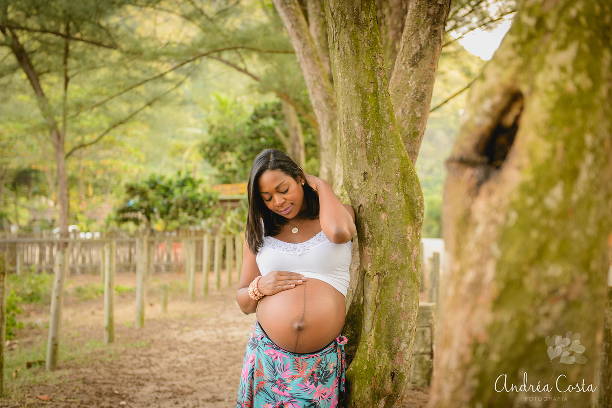 Mamãe encostada na árvore segurando o cabelo em book gestante, por Andréa Costa
