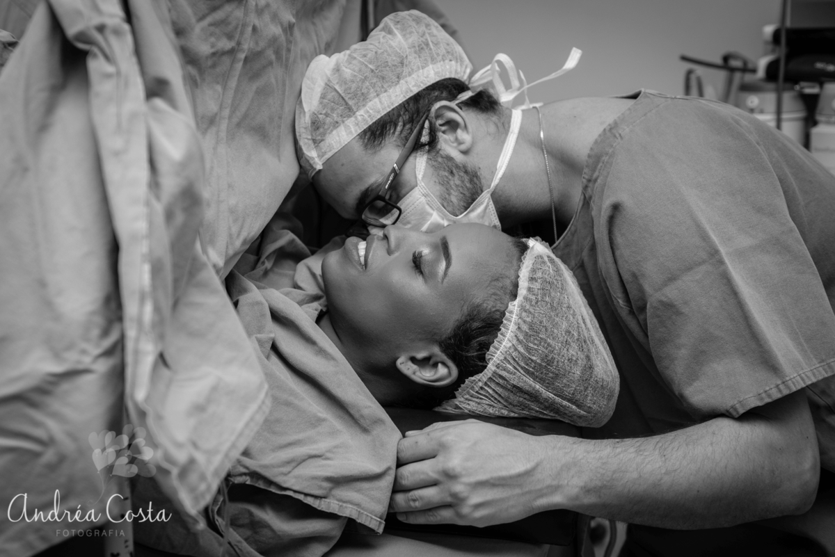 pai beijando a mãe na hora do nascimento do filho no centro cirurgico, por Andréa Costa