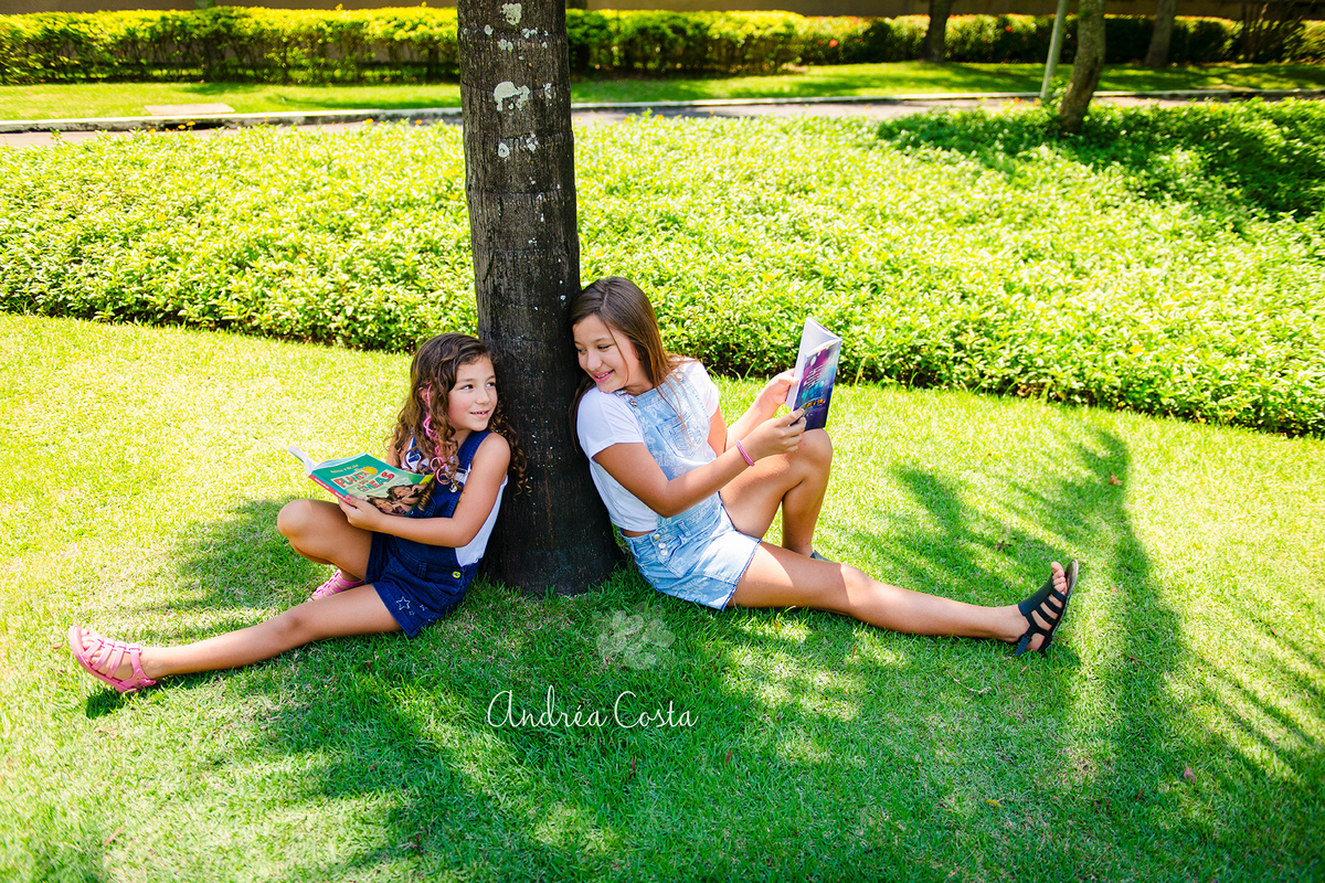 mila e manu lendo livros encostada na árvore em um parque no Rio de Janeiro, por Andréa Costa