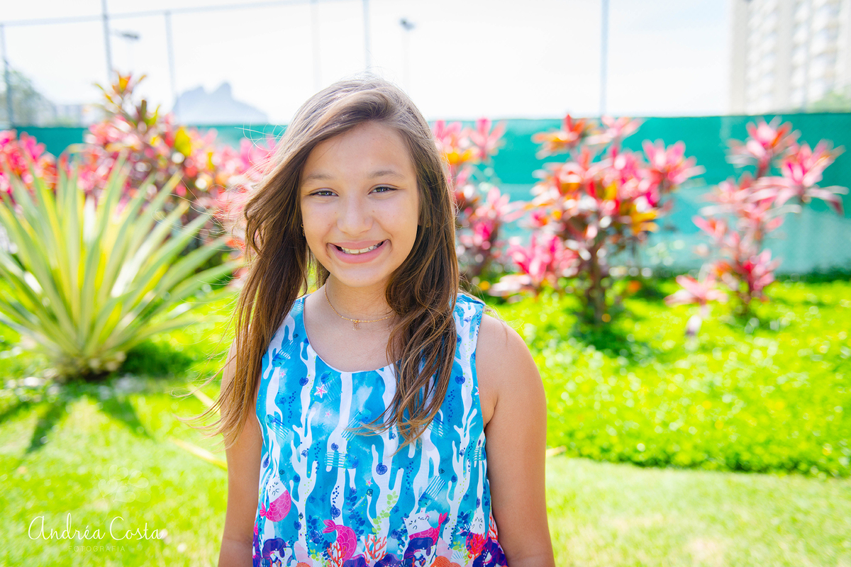retrato da manu sorrindo em lugar com bastante verde localizado na Barra da Tijuca, por Andréa Costa
