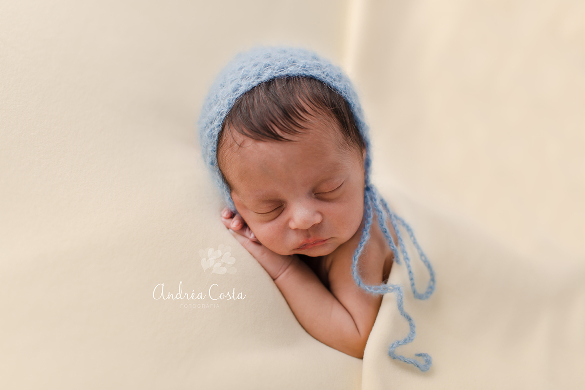 bebê com touquinha azul deitado na manta amarela em seu ensaio newborn RJ, por Andréa Costa