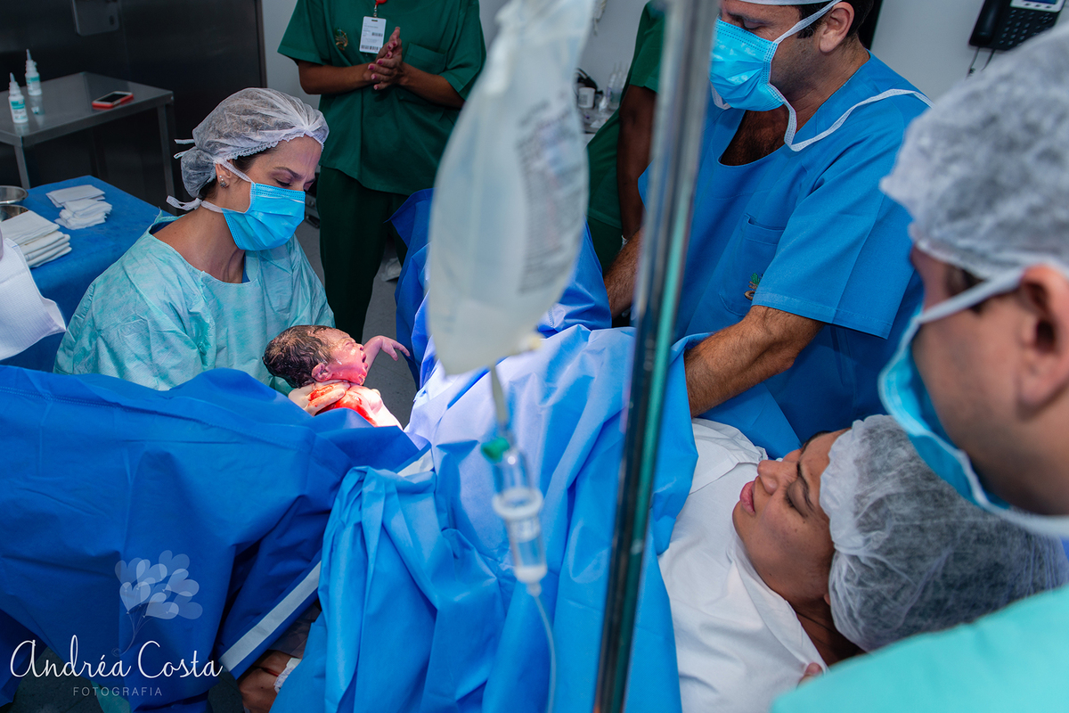 Foto colorida do momento em que o bebê está nascendo, por Andréa Costa