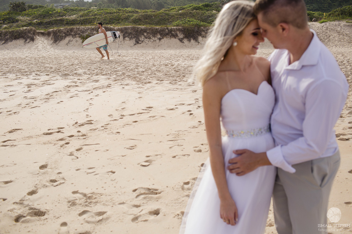 casal abraçado e surfista caminhando