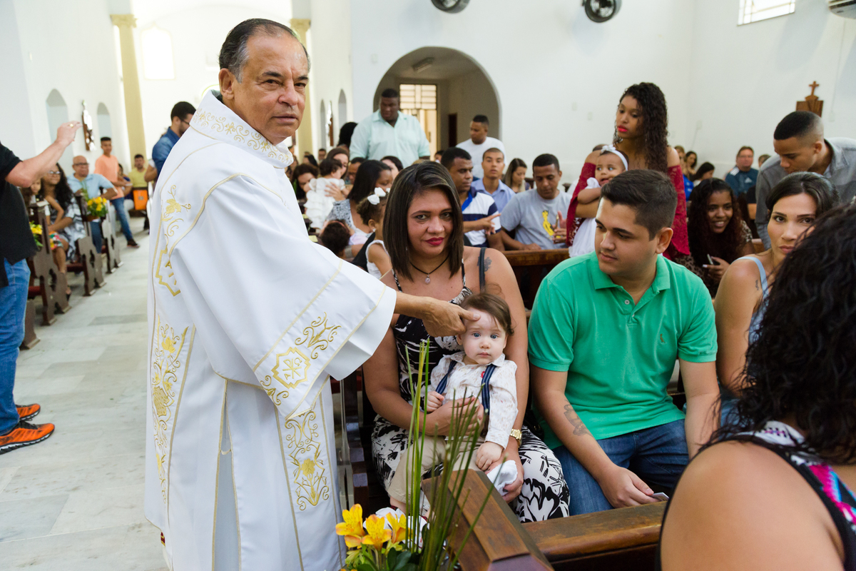 Padre crisma (unge) testa de criança com óleo durabte cerimônia de batismo