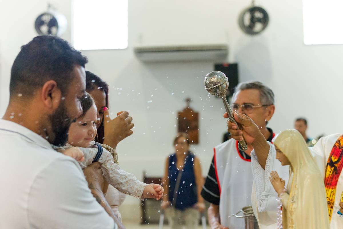 Padre benzendo criança no batizado