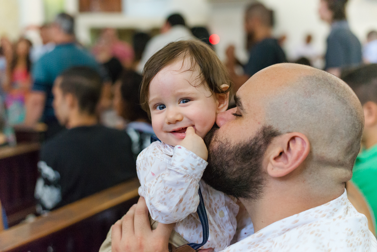 Pai beija filho durante cerimônia de batismo