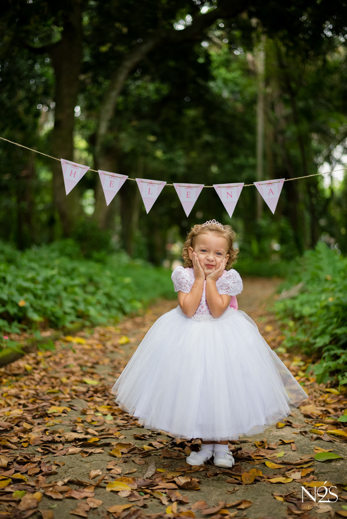 helena com as mãos no rosto com as bandeirinhas com nome no parque lage no rio de janeiro