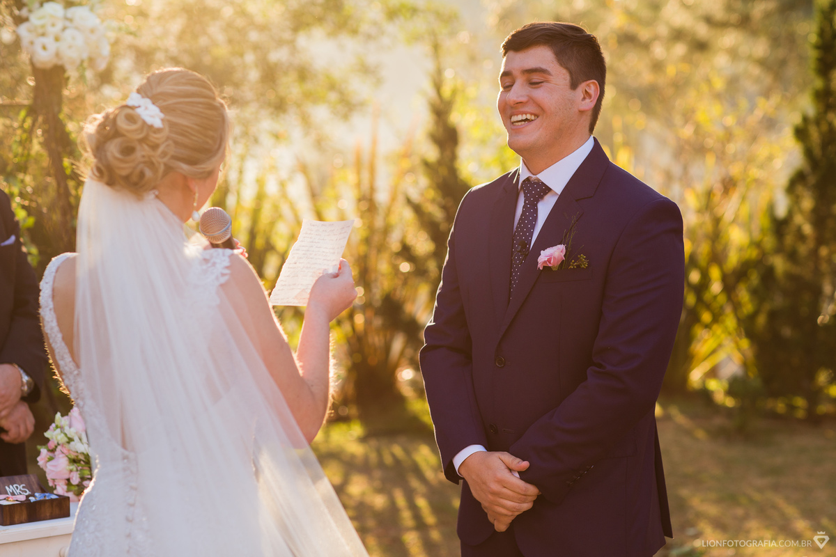 noivo sorrindo com os votos da noiva durante casamento no campo