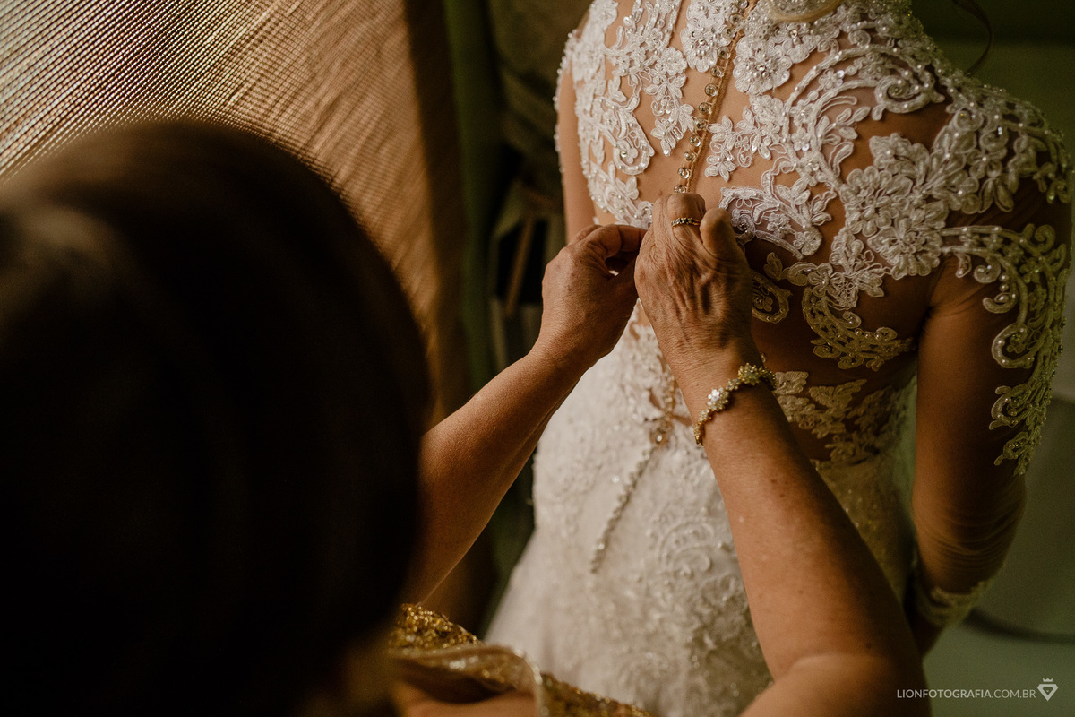 mão da noiva apertando o botão do vestido da noiva