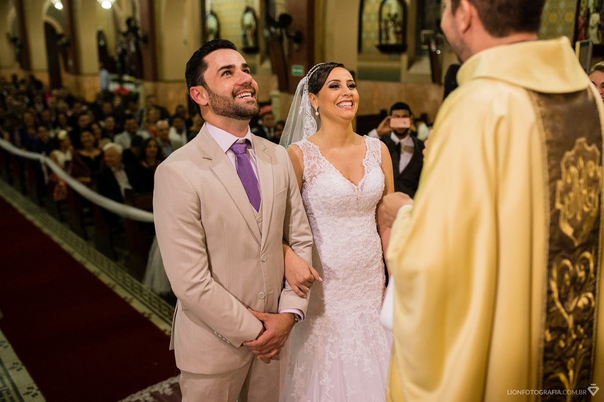 o casal muito feliz durante a celebração com o padre na igreja