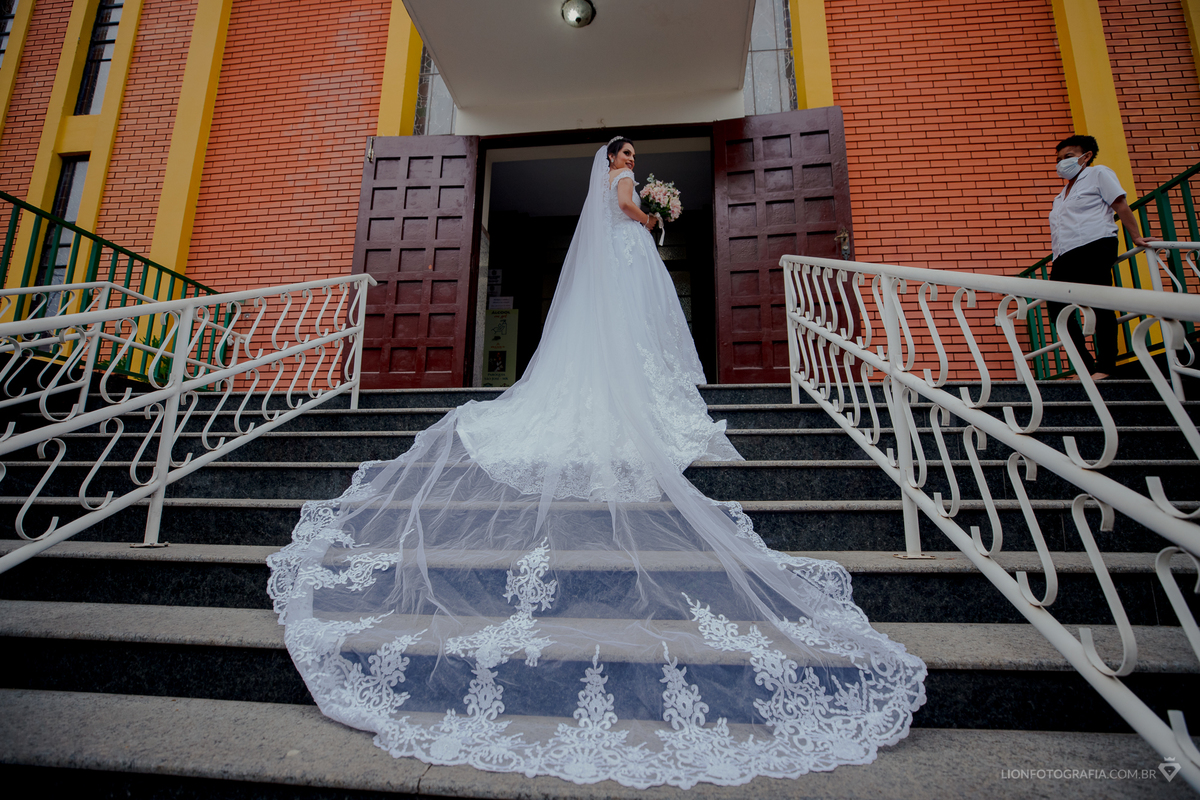 noiva na porta da igreja com seu véu na escada