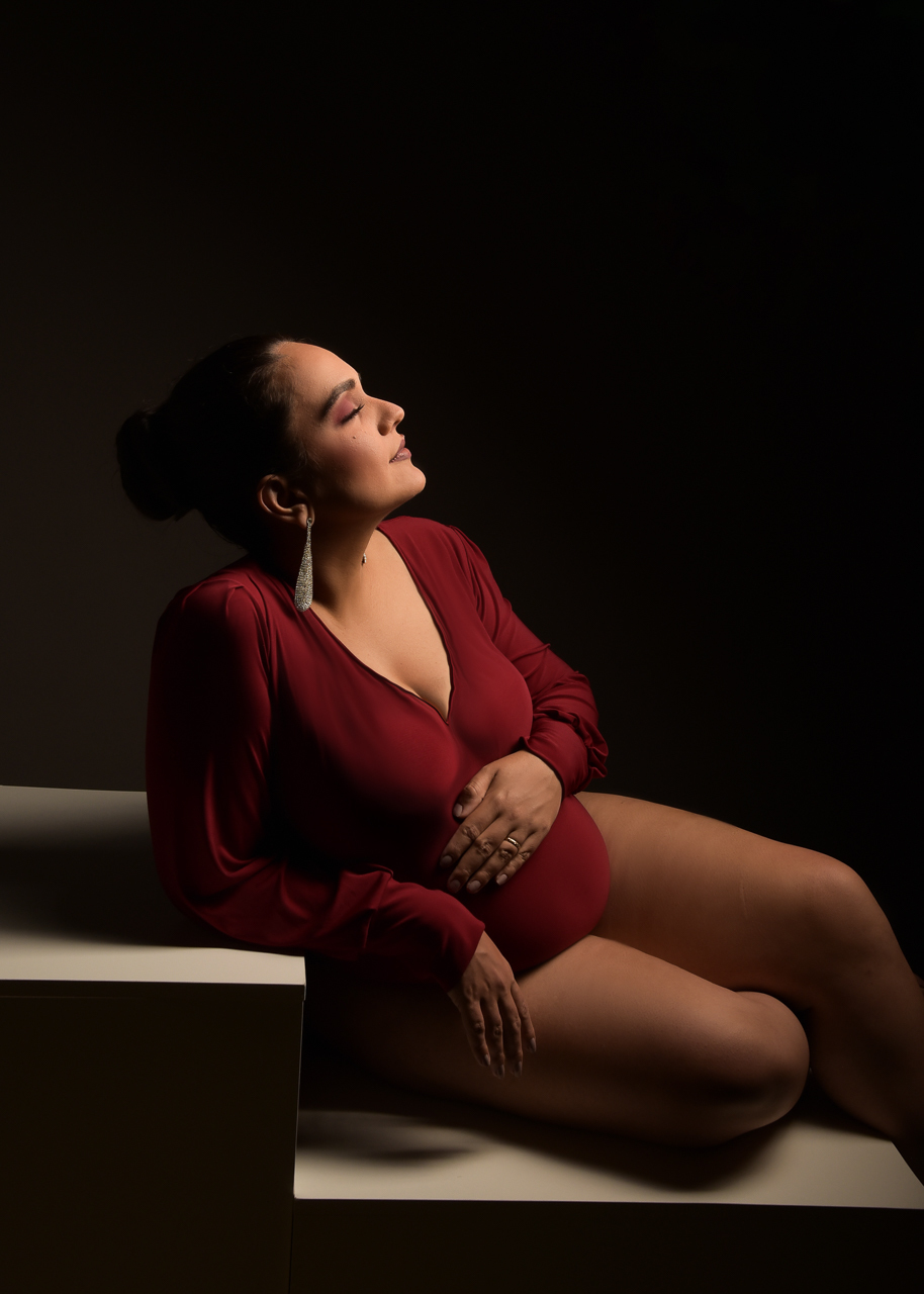 Fotografia de gestante em estúdio, iluminação controlada, enfatizando a conexão mãe e filha.