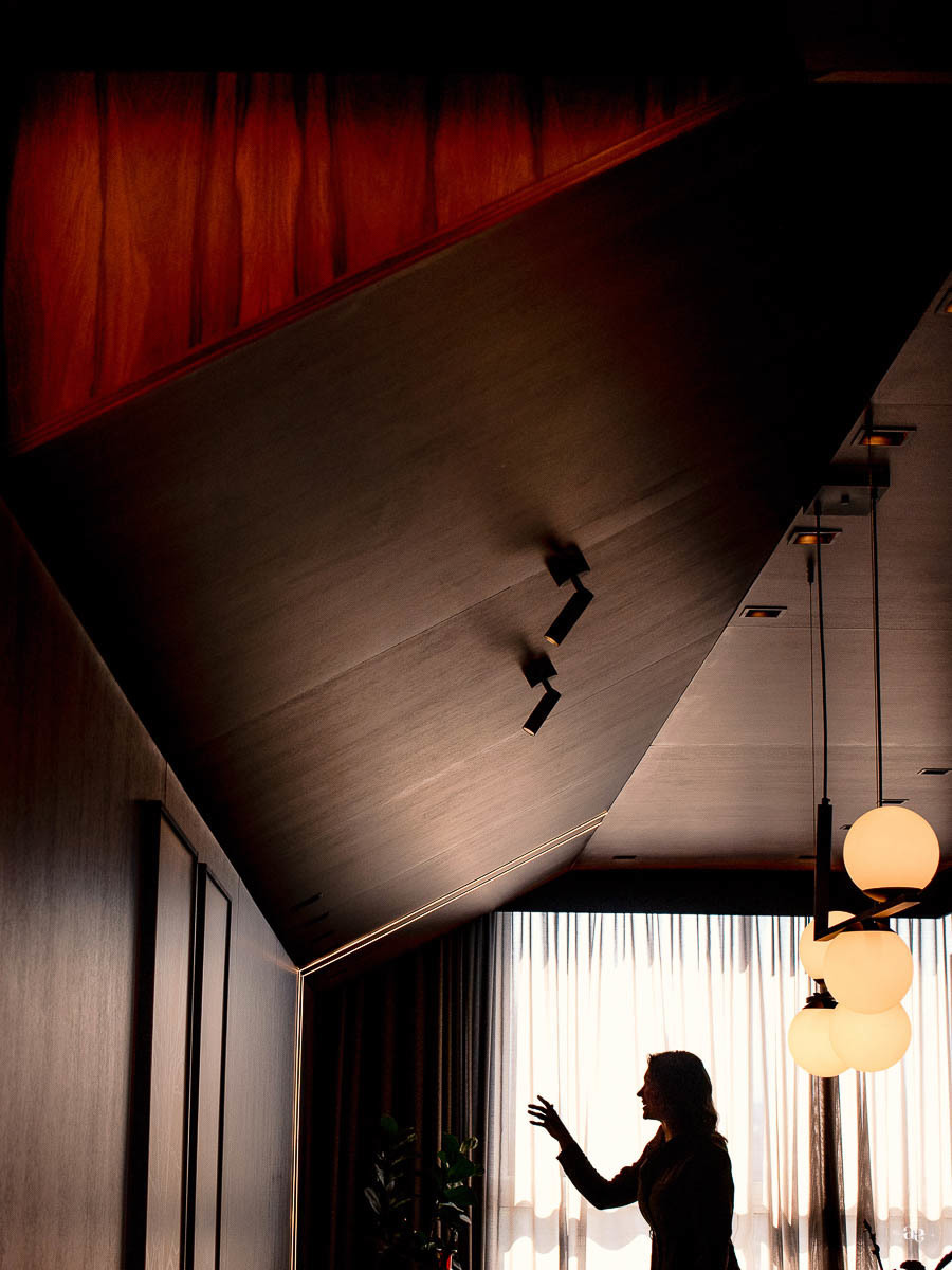 Fotografia de arquitetura contemporânea com revestimento amadeirado, linhas geométricas e iluminação decorativa, destacando os elementos visuais presentes no ensaio da arquiteta Suellen Faccio.