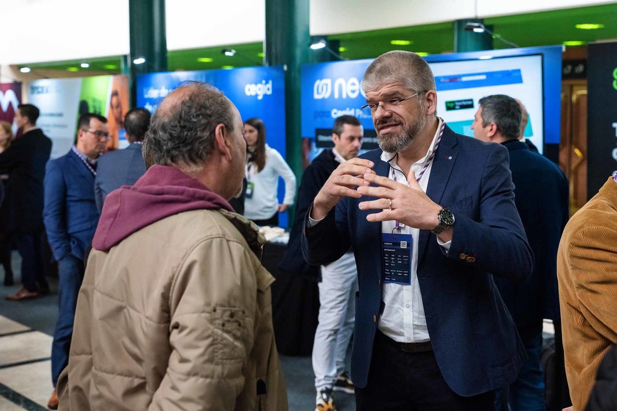 Apresentador a sorrir enquanto conversa com participantes durante intervalo informal do evento.
