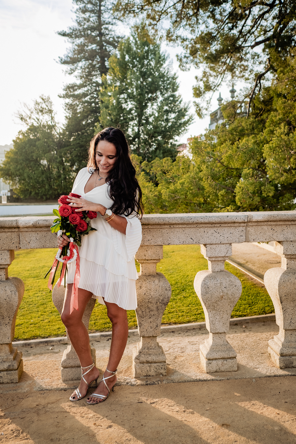 Noiva com o pôr do sol ao fundo segurando um ramo de flores silvestres