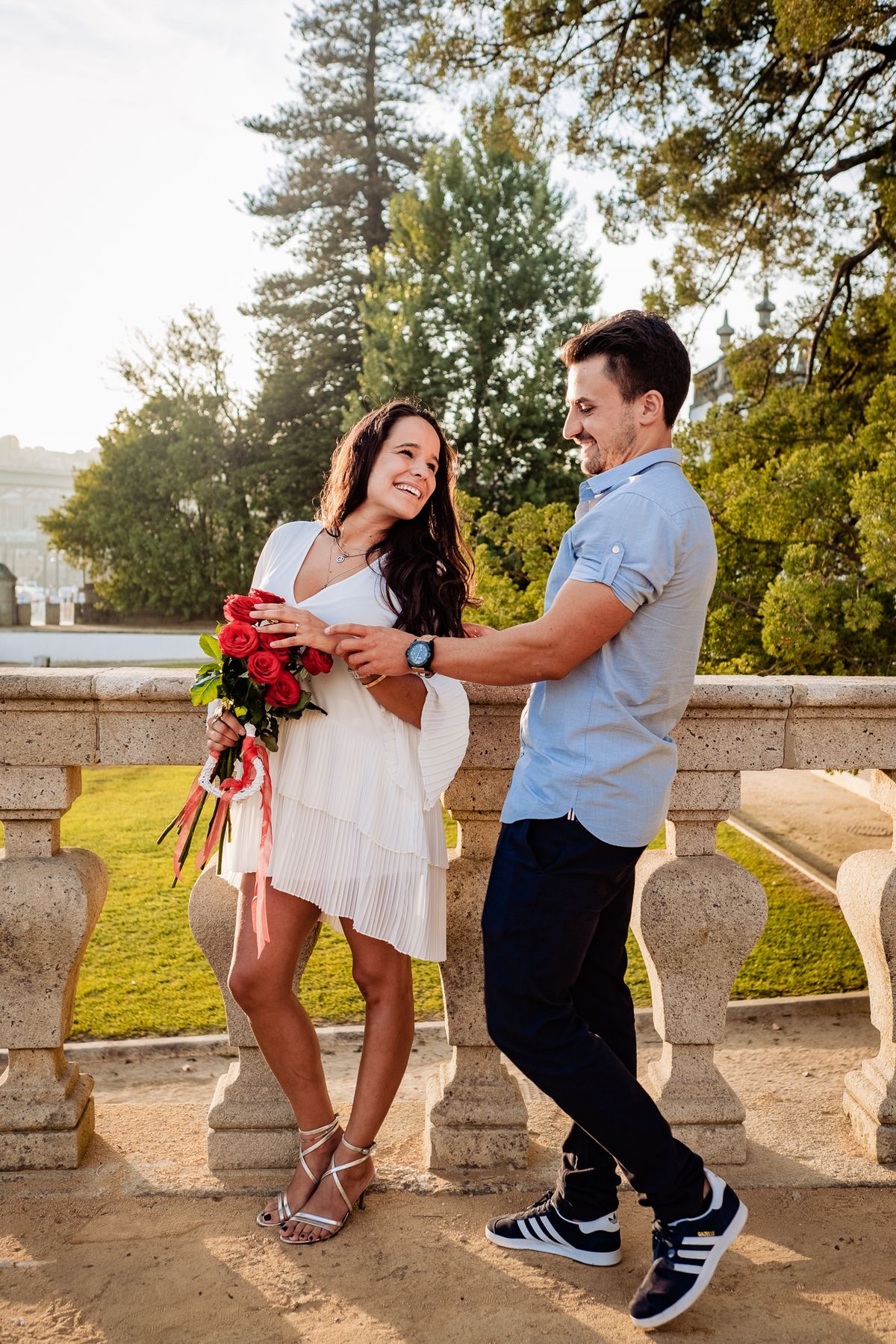 Noiva com rosas na mão a olhar intensamente para o noivo ao entardecer