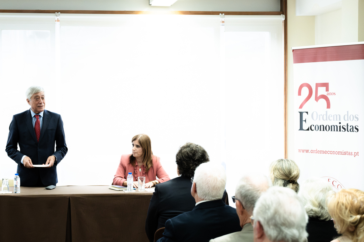 Grupo de participantes sentados em mesas redondas a debater temas económicos