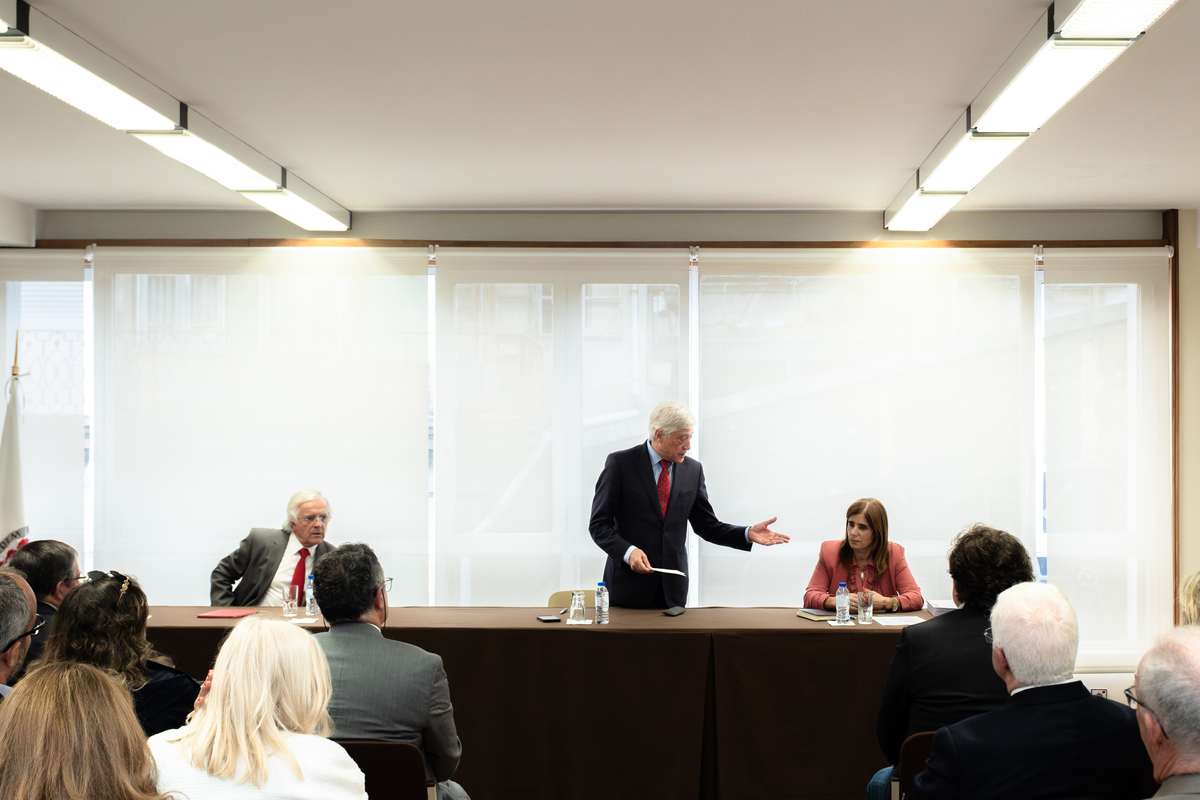 Participante em pé a fazer apresentação perante plateia atenta