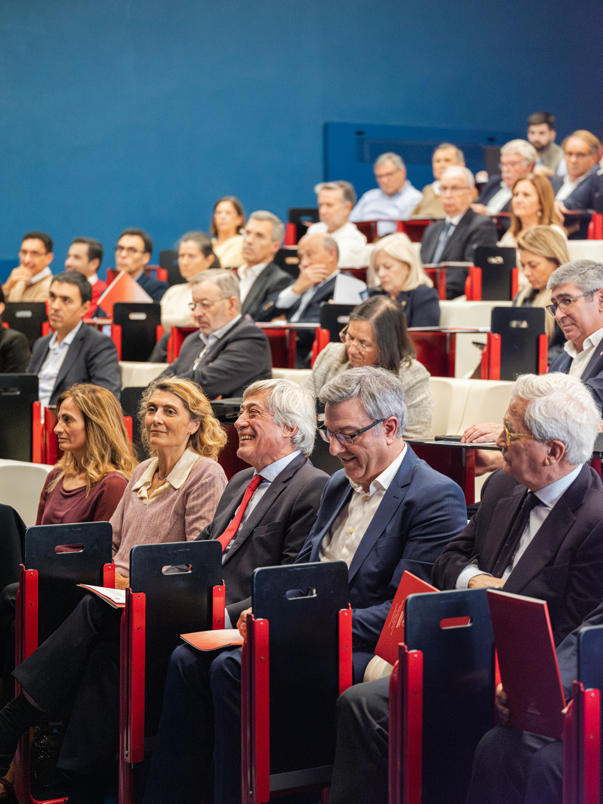 Imagem da audiência corporativa acompanhando apresentação, vista frontal ampla