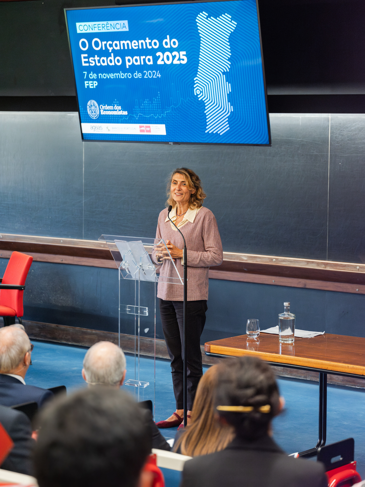 Participante focado a falar ao microfone durante painel de discussão