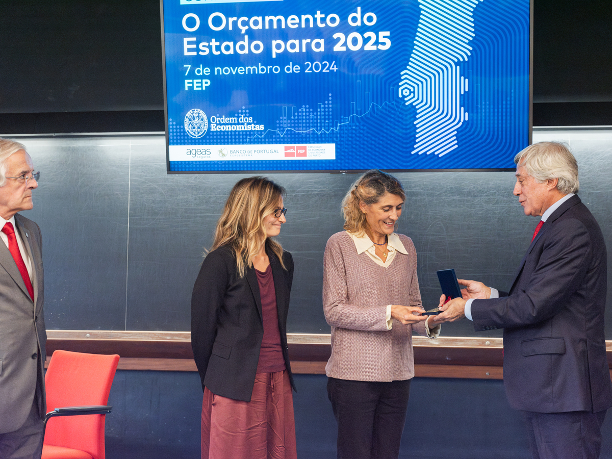 Entrega simbólica de prémio com sorriso entre vencedor e apresentador.
