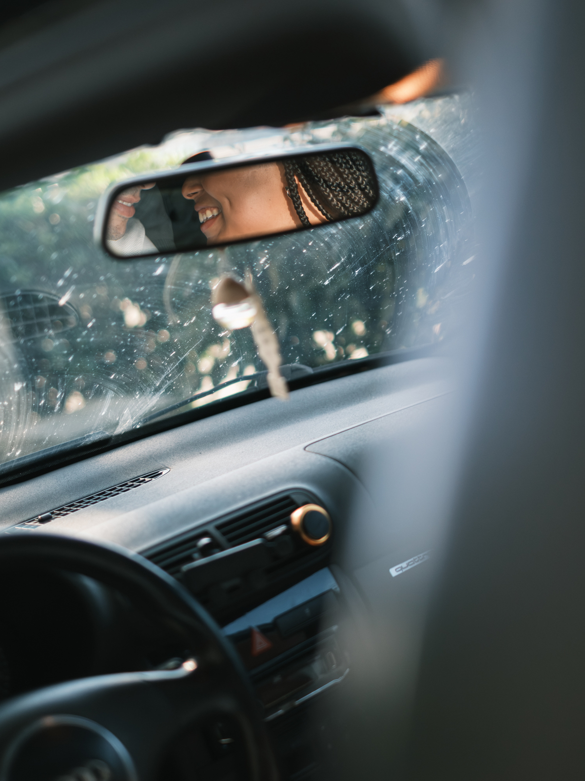 fotografia dos noivos a sorrir pelo espelho retrovisor do carro na sessão fotografica de solteiros