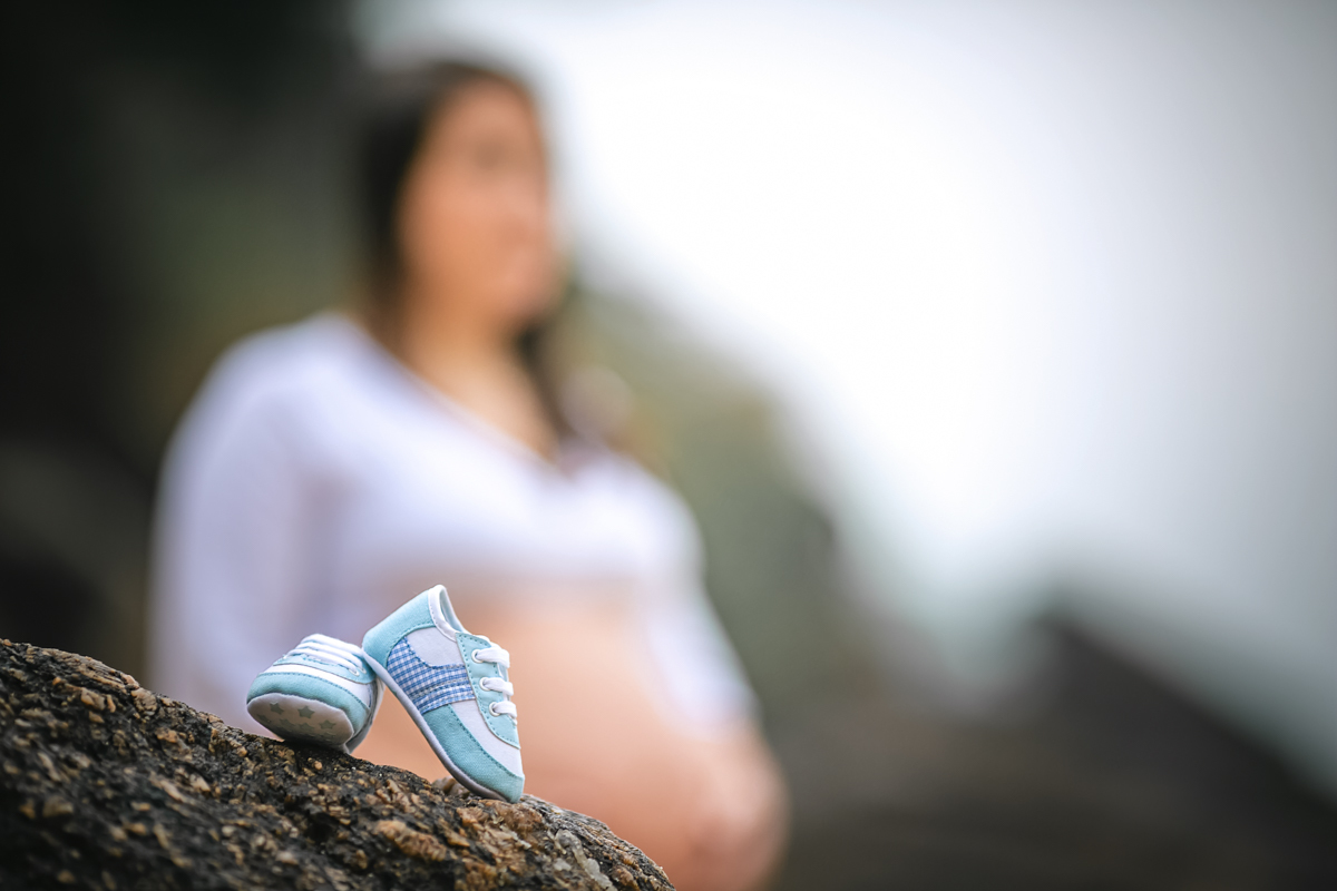 Book gestante na urca com sapatinho de bebê na pedra