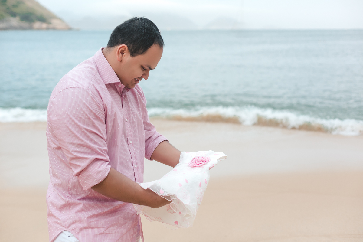 Ensaio gestante com vestidinho nas mãos do papai