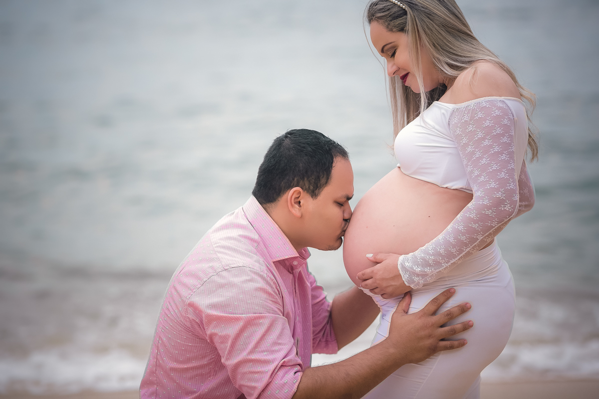 Beijo na barriga da gestante em ensaio na praia vermelha