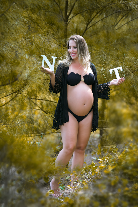 Book gestante fotográfico na praia  usando biquíni preto e saída de praia