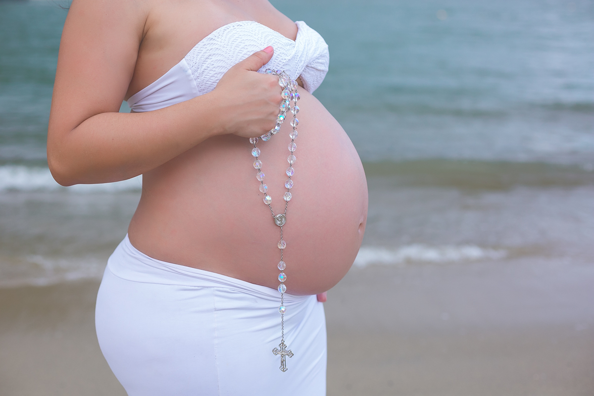 Gestante ensaio na praia com terço na barriga