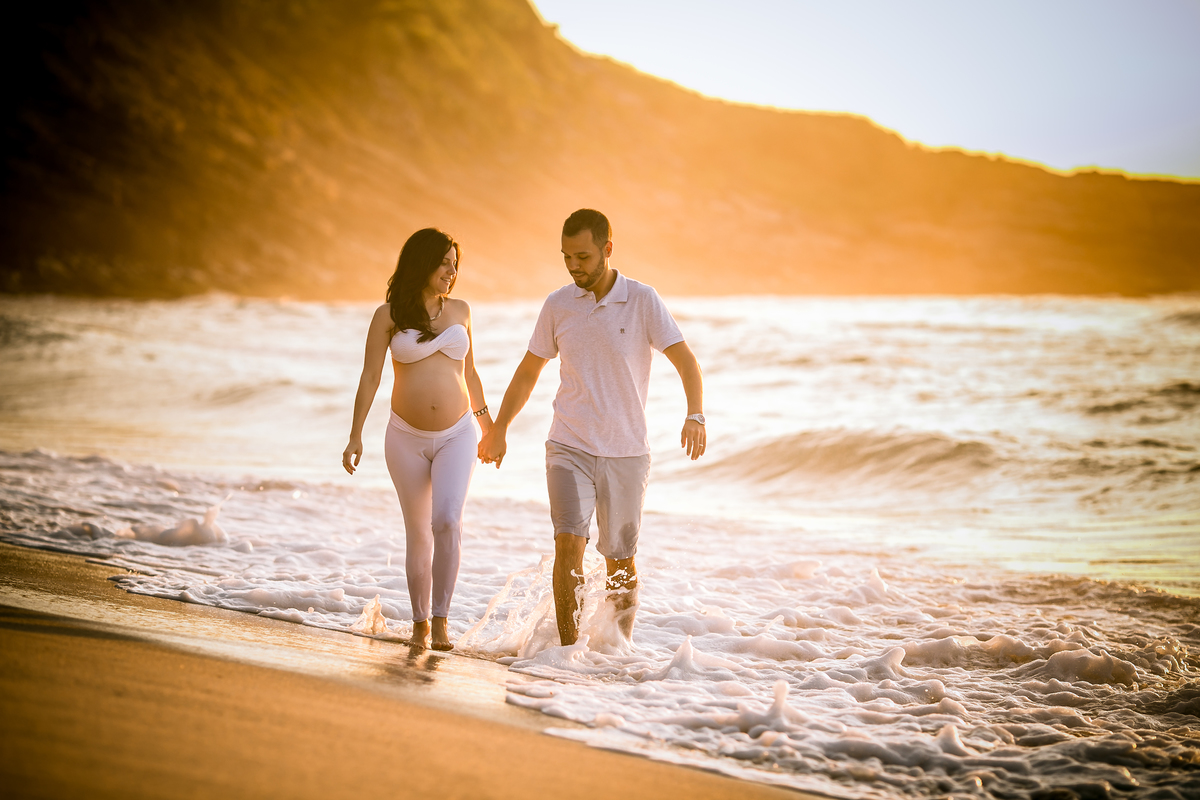 ensaio gestante Rj caminhando na areia da praia ao lado do esposo