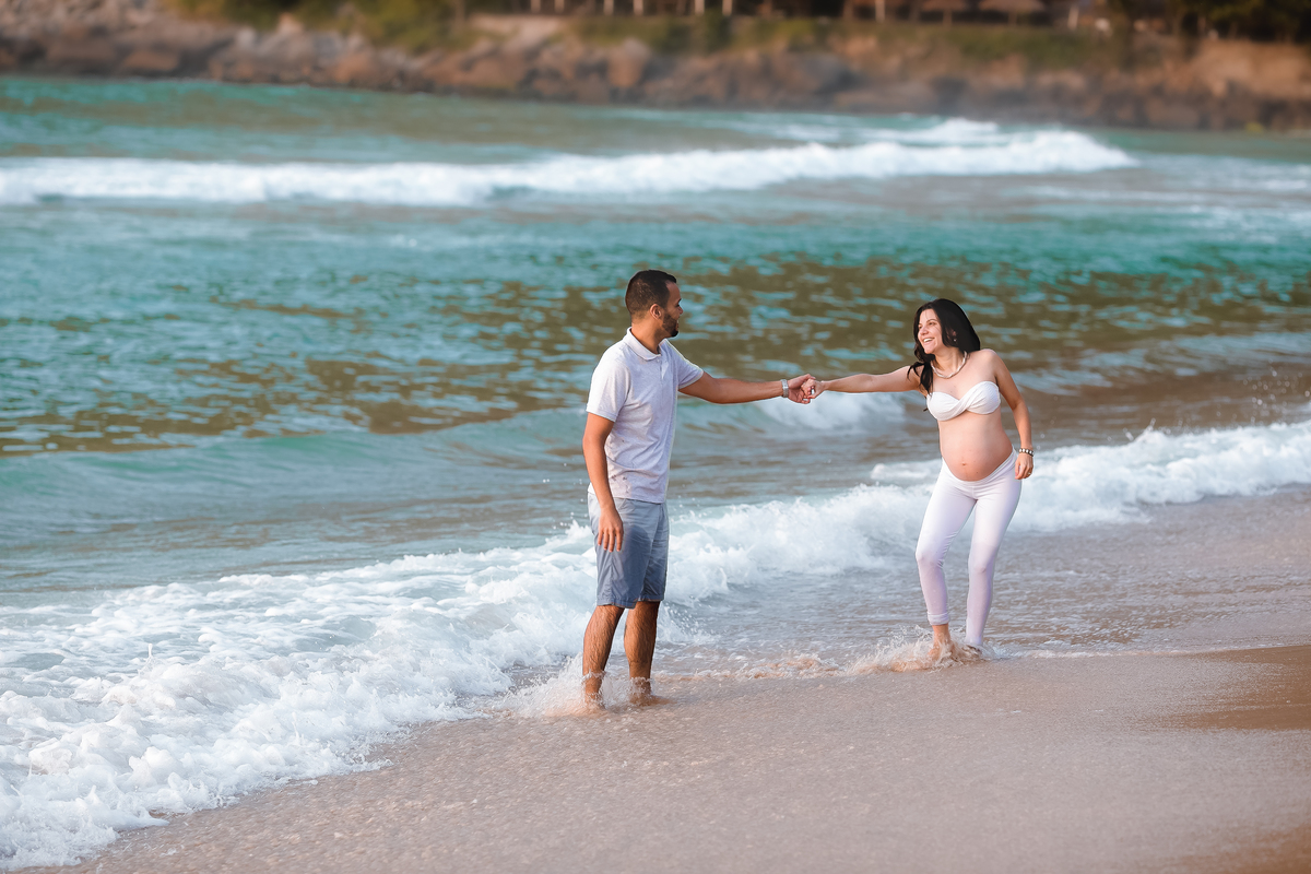 Gestante em ensaio segurando mão  do marido