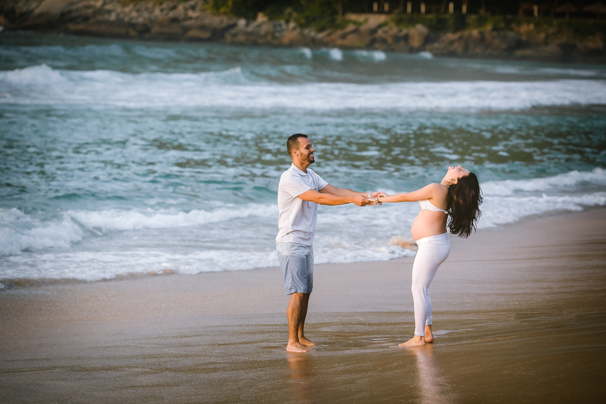 Ensaio de gestante ela brinca de jogar o cabelo para trás na praia